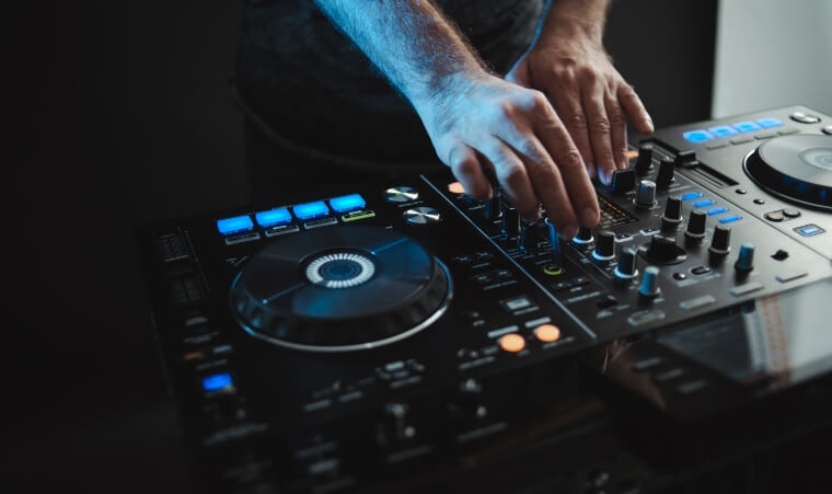 Hands performing on a DJ controller under blue light